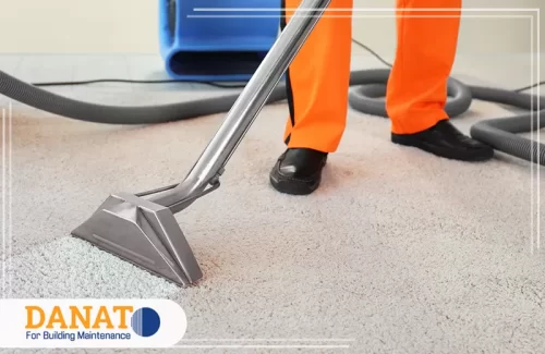 صابون تنظيف السجاد في دبي عاملًا محترفًا من شركة دانات اللؤلؤ وهو يستخدم جهاز تنظيف متخصص لإزالة الأوساخ من سجاد منزلي بجودة عالية، مع التركيز على فعالية صابون تنظيف السجاد في دبي. الجهاز يعمل بتناغم مع مواد تنظيف فعّالة