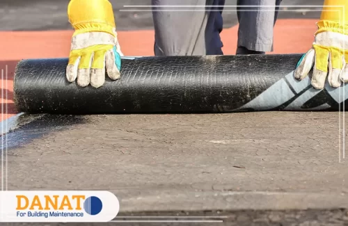 عزل الاسطح فوق البلاط برأس الخيمة 0545248958 شركة دانات اللؤلؤ فنيًا وهو يقوم بتركيب لفافة عزل أسطح فوق البلاط باستخدام معدات حماية. هذه التقنية تُستخدم لحماية الأسطح من الرطوبة والتسربات، وتعد مثالية لتطبيقات عزل الأسطح فوق البلاط في رأس الخيمة