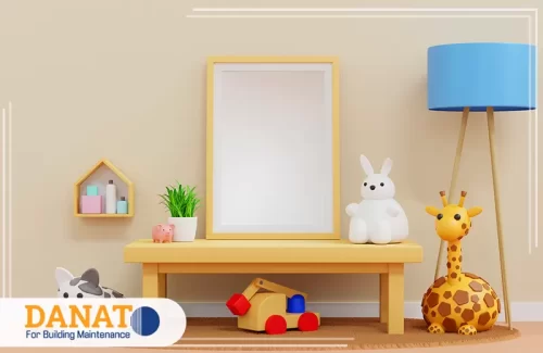 تصميم داخلي حديث عجمان 0545248958 شركة دانات اللؤلؤ ديكور غرفة أطفال بألوان هادئة يضم طاولة خشبية وألعابًا متنوعة ومصباحًا أرضيًا أزرق.